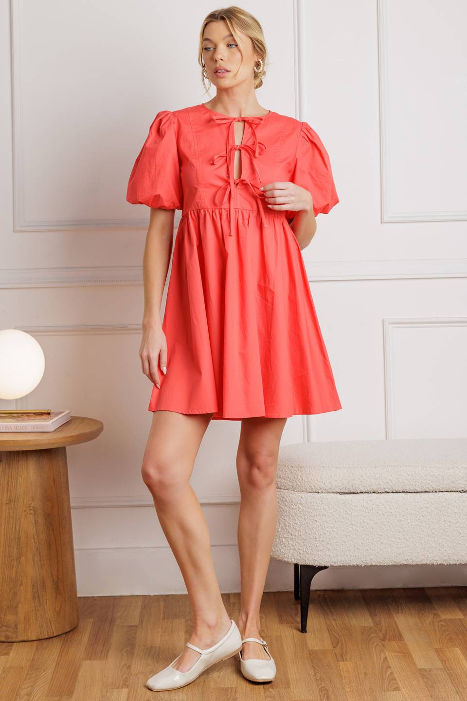 A solid woven mini dress featuring a round neckline, front bow ties, and short puff sleeve from Flying Tomato